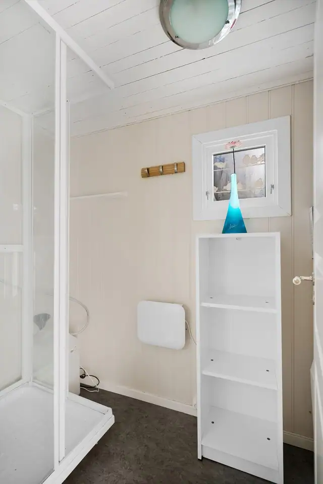 Bad med dusjkabinett og panel på vegger - praktisk innredning og vindu som slipper inn dagslys
