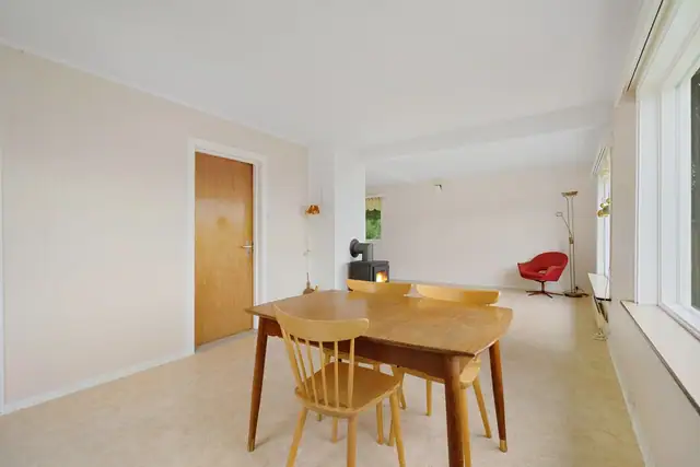 Lys stue med plass til både spisebord og sofagruppe - og en vedovn som gir lun stemning