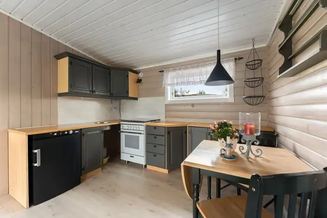 Kjøkken med profilerte fronter og benkeplate av laminat. Kjøkkenet er utstyrt med gasskjøleskap og gasskomfyr.