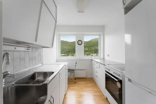 Kjøkken med glatte fronter og nyere benkeplate i laminat. Utstyrt med kjøl/fryseskap, komfyr, stålvask og vannstoppsystem.