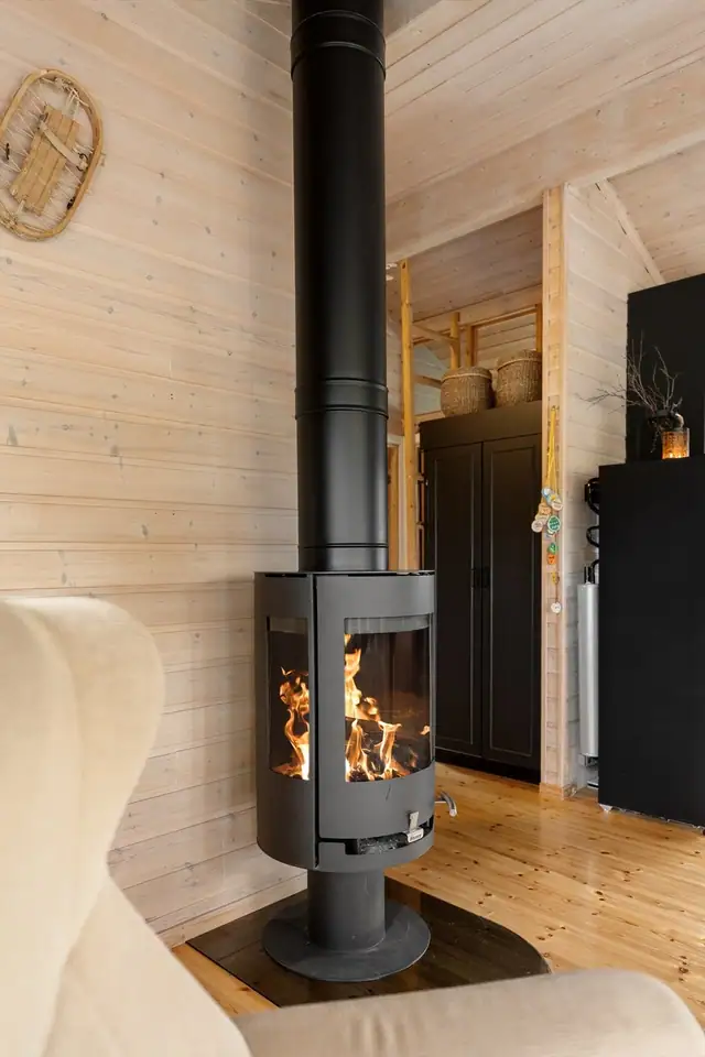 Vedfyring som skaper en lun og hyggelig atmosfære i stuen - perfekt for koselige kvelder på hytta.