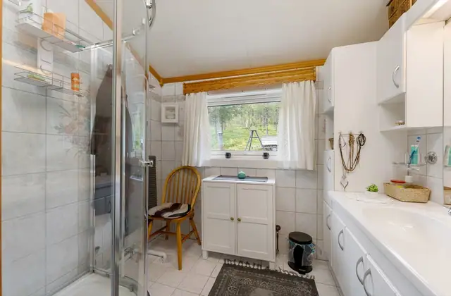 Badet har flislagte vegger og himling med himlingsplater. Våtrommet er innredet med servantinnredning med heldekkende servant og dusjkabinett, og fremstår som et praktisk og funksjonelt bad.