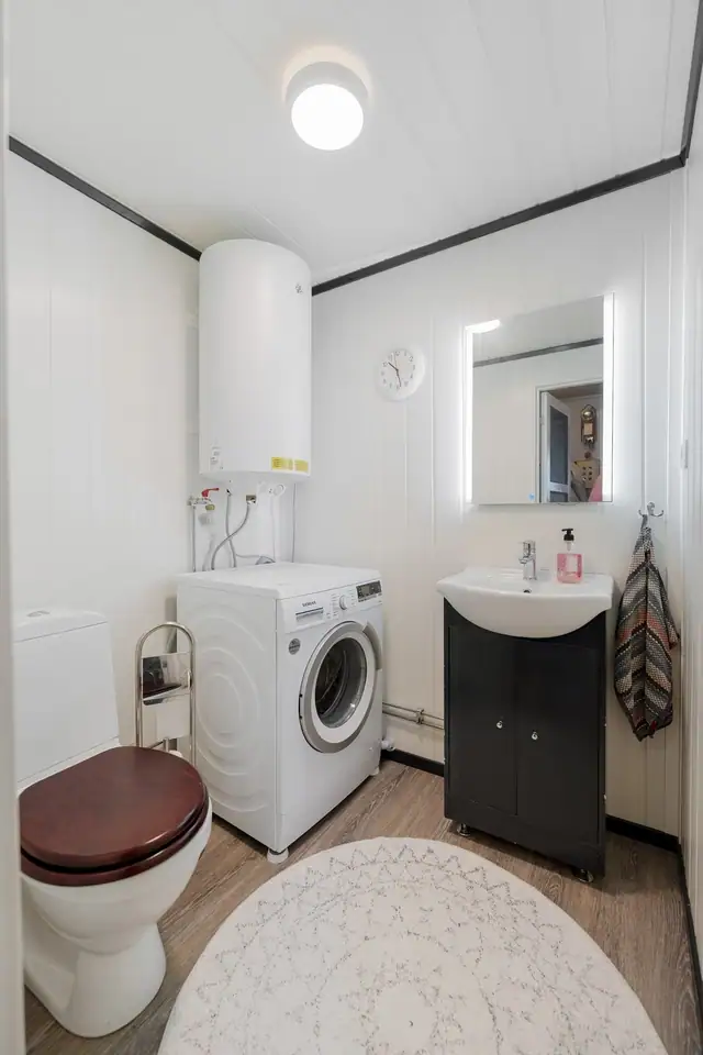 Toalettrom-Gulvet har gulvbelegg, og badet er utstyrt med toalett, servant med underskap og opplegg for vaskemaskin. En praktisk og funksjonell løsning for boligens hverdag.