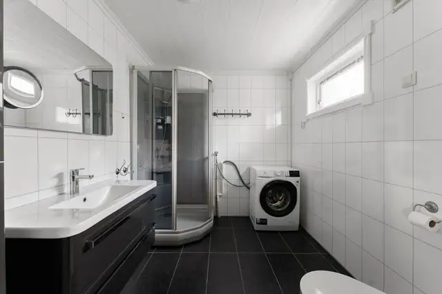 Stilrent bad med behagelige varmekabler i gulvet. Badet er innredet med nedfelt servant, veggmontert toalett, dusjkabinett og opplegg for vaskemaskin.