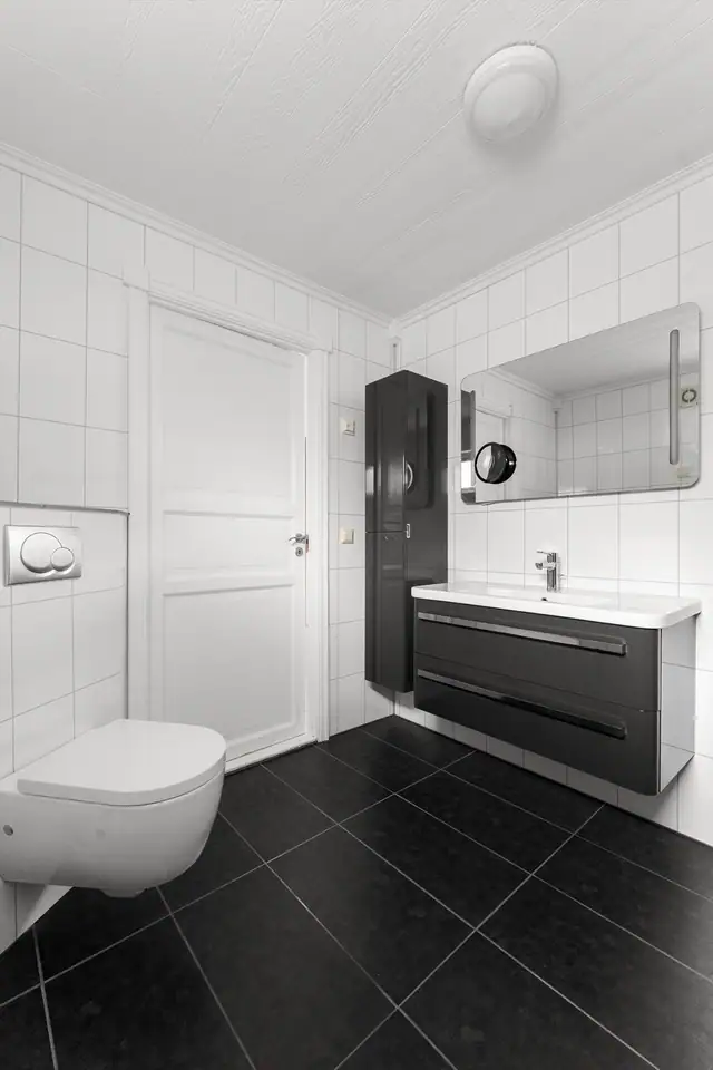 Badet har høyskap og praktiske oppbevaringsløsninger, samt speil med integrert belysning.