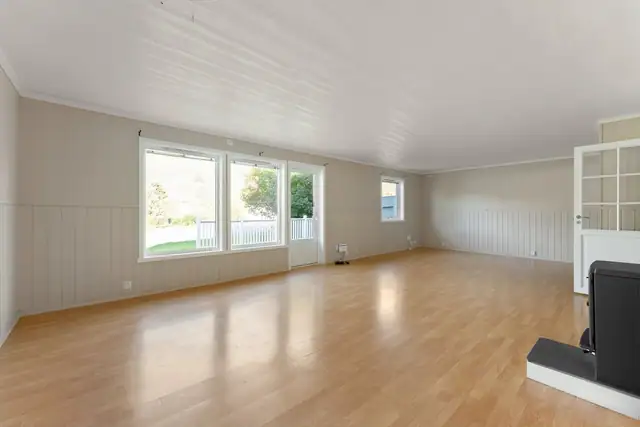 Stor og innbydende stue med rikelig med vindusflater som slipper inn godt med naturlig lys - et hyggelig rom for både avslapping og sosialt samvær.