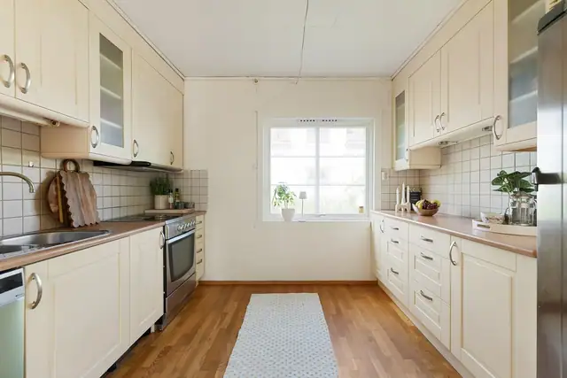 Kjøkken med profilerte fronter og benkeplate i laminat. Kjøkkenet inneholder stekeovn, oppvaskmaskin og ventilator.