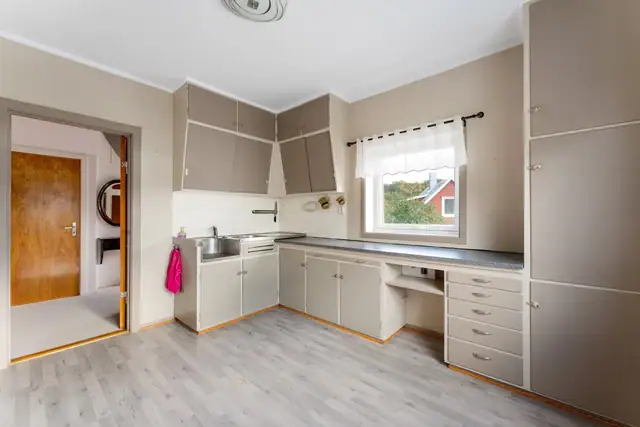Kjøkkenet har en praktisk innredning med glatte fronter, rikelig med skapplass og gode arbeidsflater. Benkeplaten er utført i laminat og rustfritt stål.