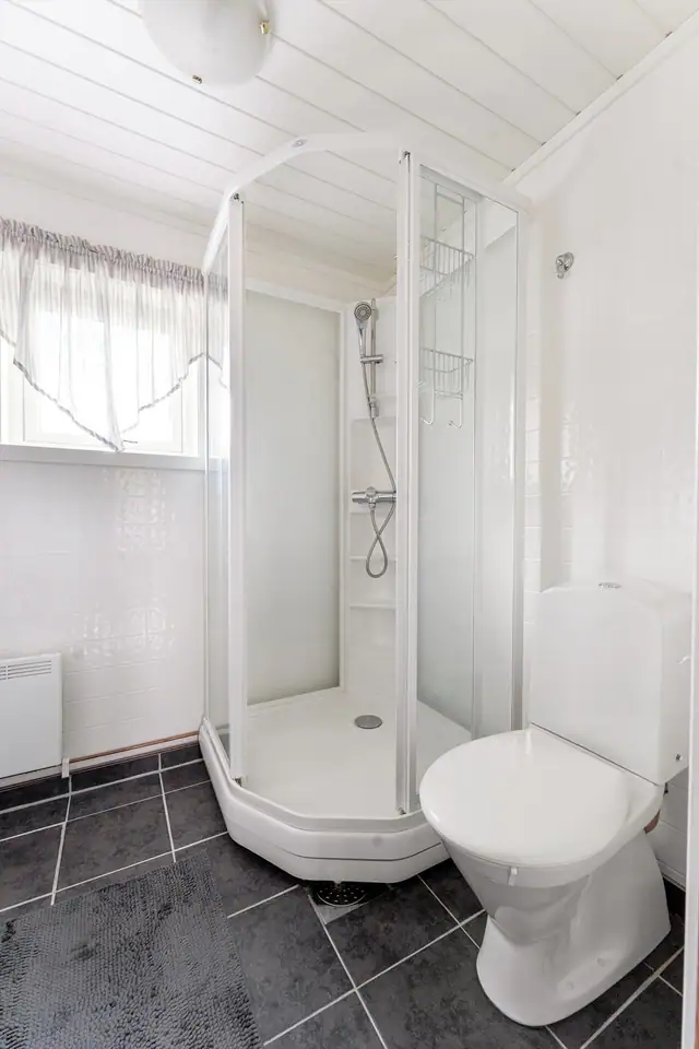 Badet er innredet med nedfelt servant, toalett og dusjkabinett.