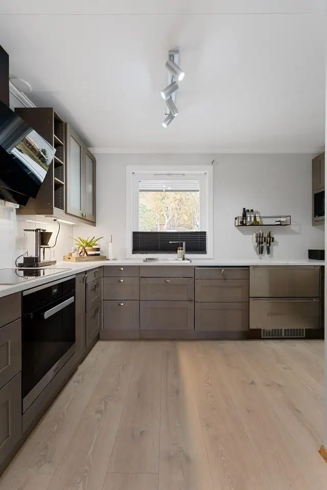 Moderne Sigdal kjøkkeninnredning fra 2018 med beisede fronter og enkel profil, kombinert med en stilren benkeplate i kompositt.