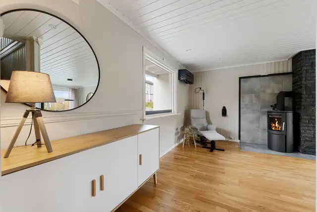 Romslig og innbydende stue med vedfyring, gode lysforhold og en luftig romfølelse som skaper en varm og hyggelig atmosfære.