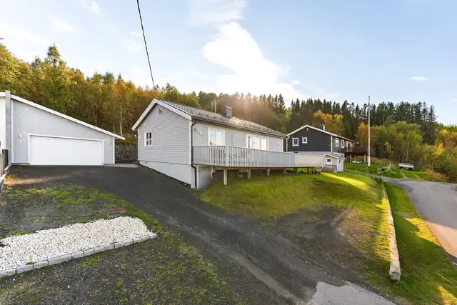Skrånende og opparbeidet tomt med gruset innkjøring og gårdsplass. Terrenget er tilpasset med flere forstøtningsmurer i betong og elementstein, samt avskjærende drenering for håndtering av overflate- og terrengvann.