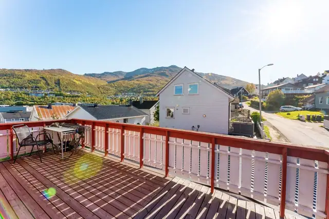 Romslig og solrik veranda som strekker seg langs to sider av huset, med god plass til møblering.